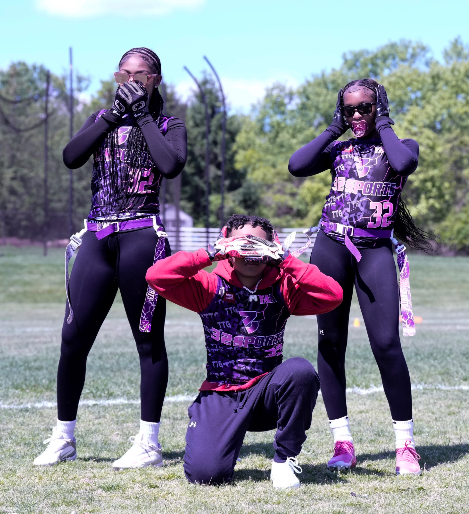 Three 32 Sports flag football teammates posing together on the field