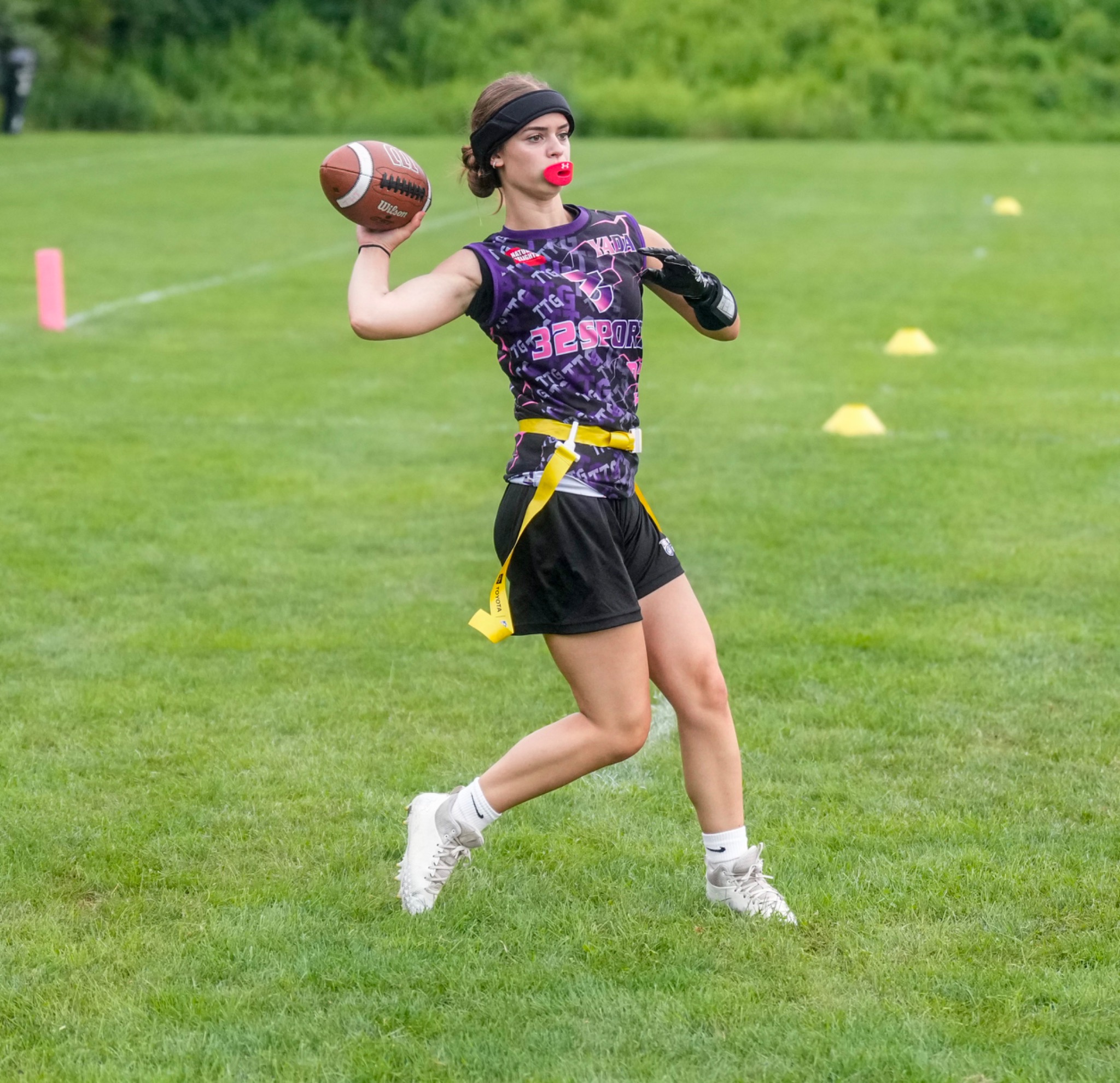 32 Sports quarterback throwing a football with yellow flags at her waist