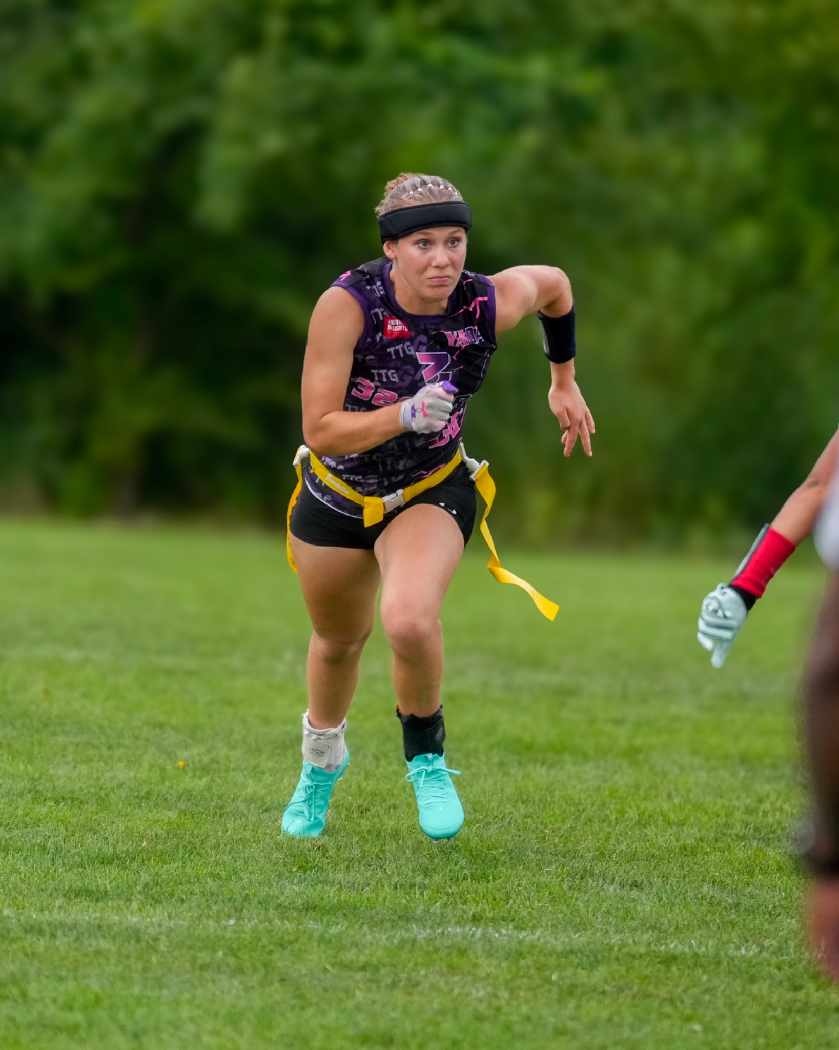 32 Sports athlete sprinting in teal cleats with yellow flags