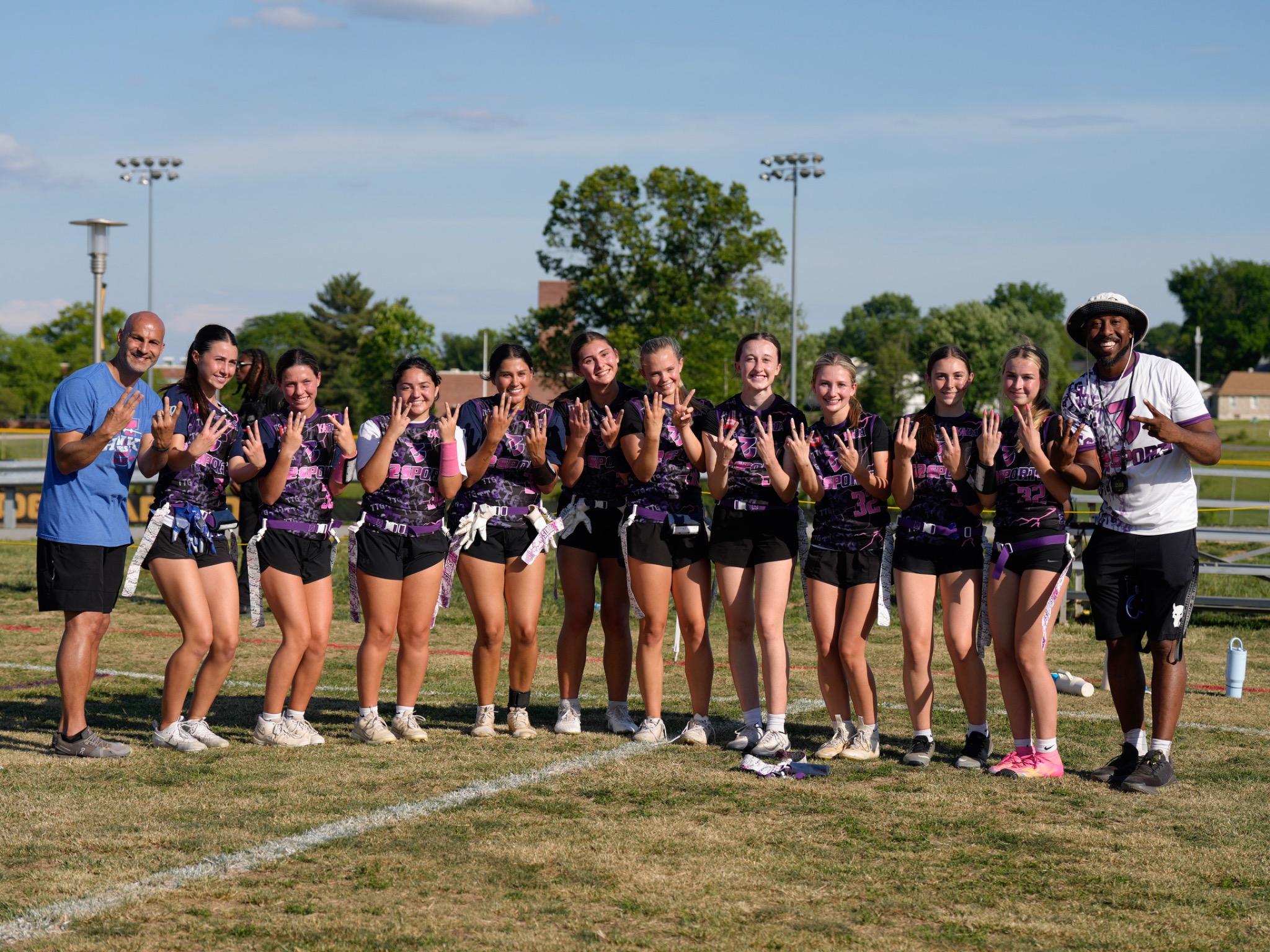 32 Sports girls flag football team and coaches together on the field
